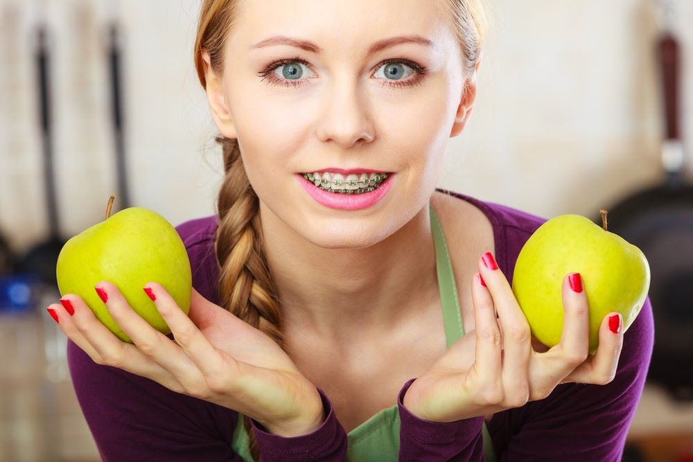 Adult with braces eating an apple